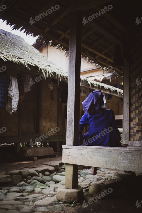 Preview: A Vertical Shot Of A Female Sitting Outdoors In A Traditional Indonesian House