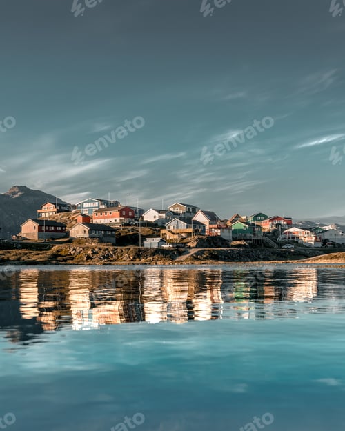 Preview: A Vertical Shot Of Colorful Houses On A Hill Reflected On A Frozen Lake During The Winter