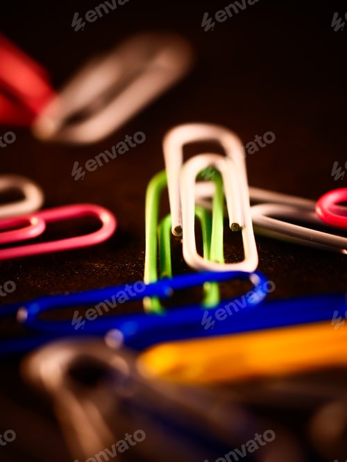 Preview: A Vertical Selective Focus Shot Of Colorful Paperclips Scattered On The Floor In The Office