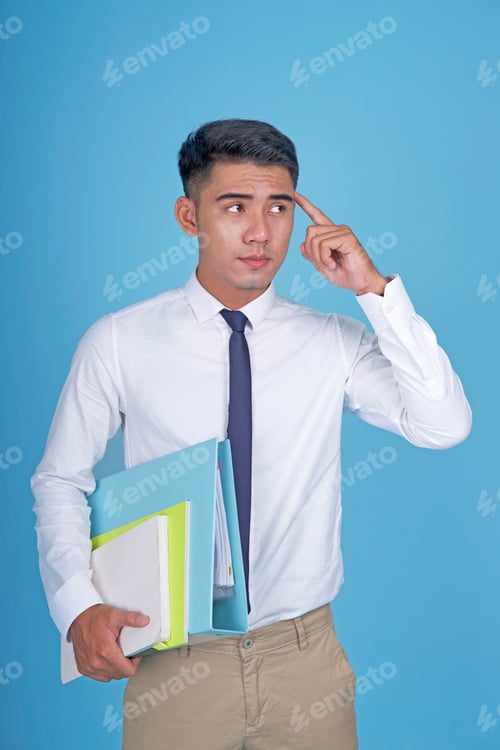 Preview: Asian Young Handsome Student With Book And Thinking, On Light Blue Background