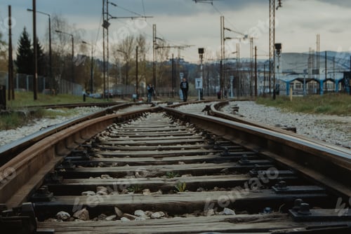 Preview: A Railway With People In The Background Under A Gray Cloudy Sky