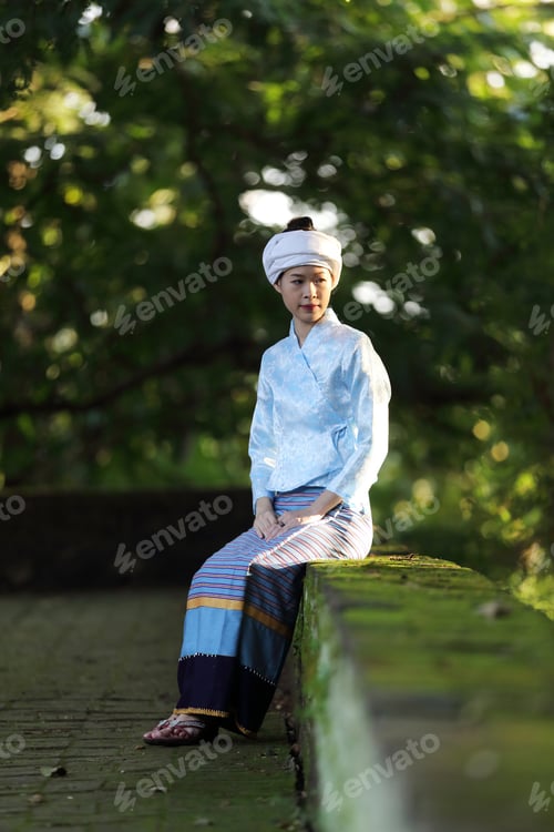 Preview: Portrait Of Thai Young Woman With Traditional Thai Dress Sit In Thai Temple With Tree And Sunrise
