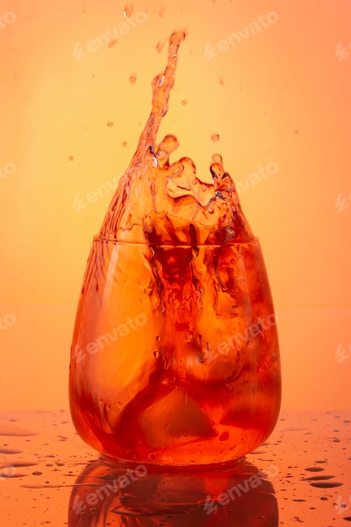Preview: A Vertical Shot Of An Orange Cocktail Splash On An Orange Background