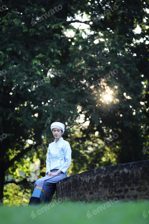 Preview: Portrait Of Thai Young Woman With Traditional Thai Dress Sit In Thai Temple With Tree And Sunrise