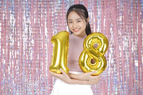 Visualização: Jovem adolescente asiática, linda e alegre, com balão dourado para festa, em rosa cintilante