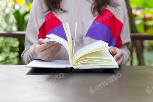 Preview: Woman Hands Open Book With Blank Pages On Wooden Table.