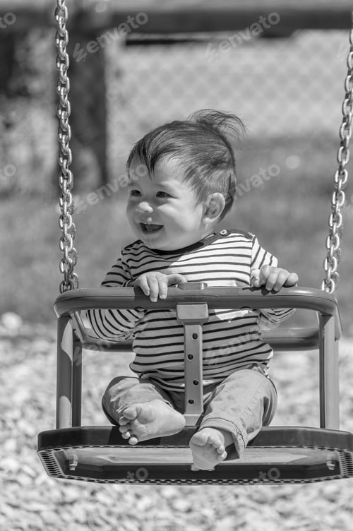 Preview: A Vertical Grayscale Closeup Shot Of A Male Child On A Swing