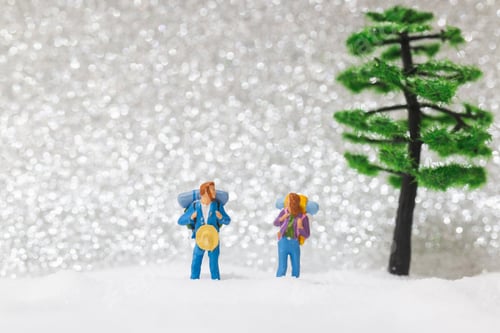 Preview: Miniature People: Backpacker Walking On Snow Background . Winter Concept.