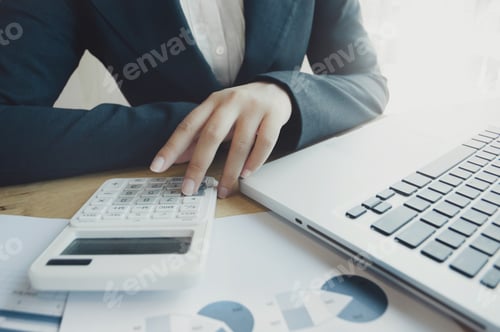 Preview: Business Woman Analyzing On Graph Paper With Calculator And Laptop At The Office