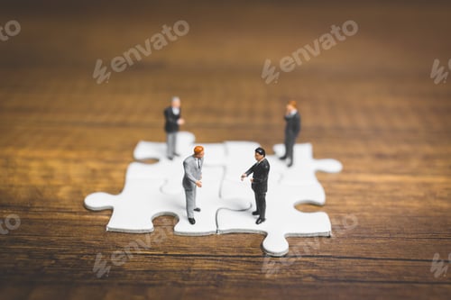 Preview: Miniature People: Businessman Standing On Jigsaw With Wooden Background : Business Concept.