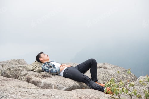 Preview: Young Hipster Man Lying On The Rocks In The Mountains