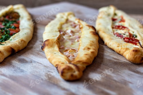 Preview: A Closeup Of Appetizing Pide Flatbread Variety Stuffed With Toppings On A Wooden Surface
