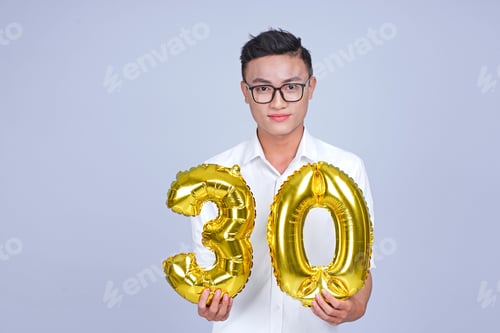 Vista previa: Asian Young Handsome Attractive Male Student Holding Metallic Foil Balloon With Number