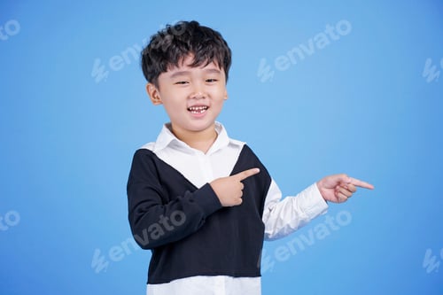 Preview: Close Up Portrait Of Cute Boy Pointing With Finger Gesture, Isolated On Blue Background