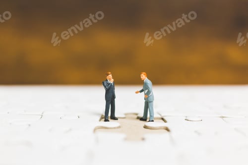 Preview: Miniature People: Businessman Standing On Jigsaw With Wooden Background : Business Concept.