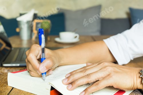 Preview: Businessman Writing Note On Oreading Book With Laptop On Table.