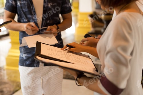 Preview: Group Of Tourist Getting Key Card From Hotel Receptionist With A Greement Form In Her Hand