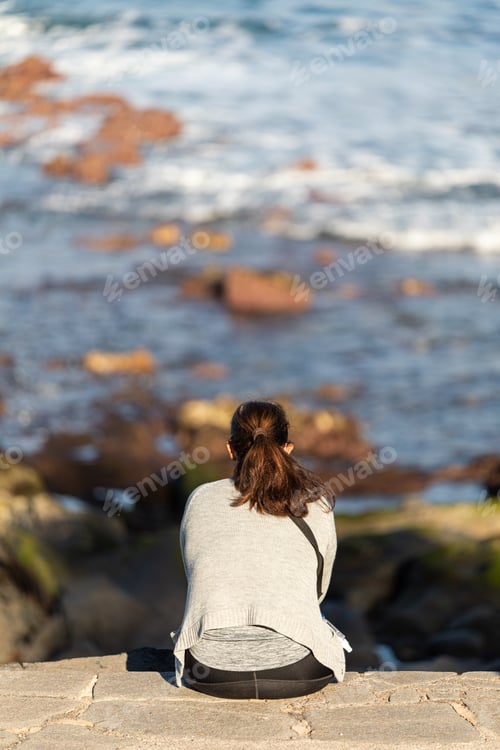 Preview: A Rear View Of A Lonely Woman Sitting On A Rocky Surface