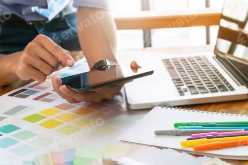 Preview: Creative Businessman Using Tablet And Working On Colour Charts On Desk At A Modern Office