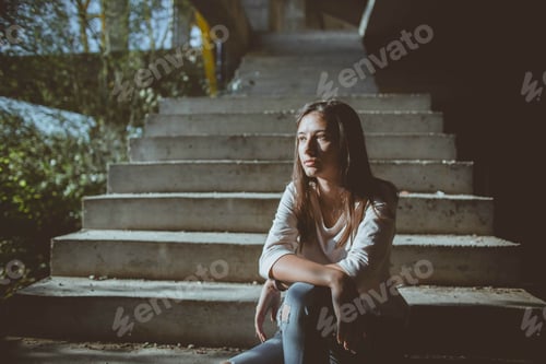 Preview: A Caucasian Female With A Thoughtful Expression Sitting On Outdoor Stairs At Night
