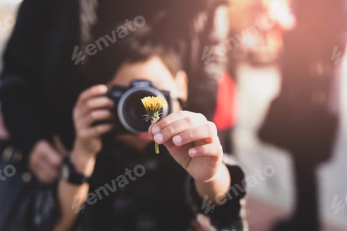 Preview: Young Boy With Mother Taking Photos Of Yellow Flower On Vacation In Cinematic Color