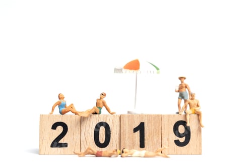 Visualização: Pessoas em miniatura vestindo traje de banho relaxando em bloco de madeira 2019 com fundo branco