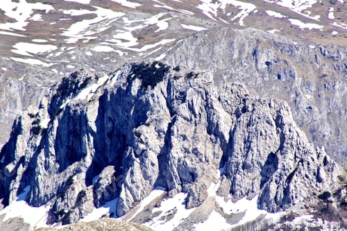 Preview: A Rocky Cliff In A Mountainous Region Covered By Snow With Bright Sunlight Shining Upon It