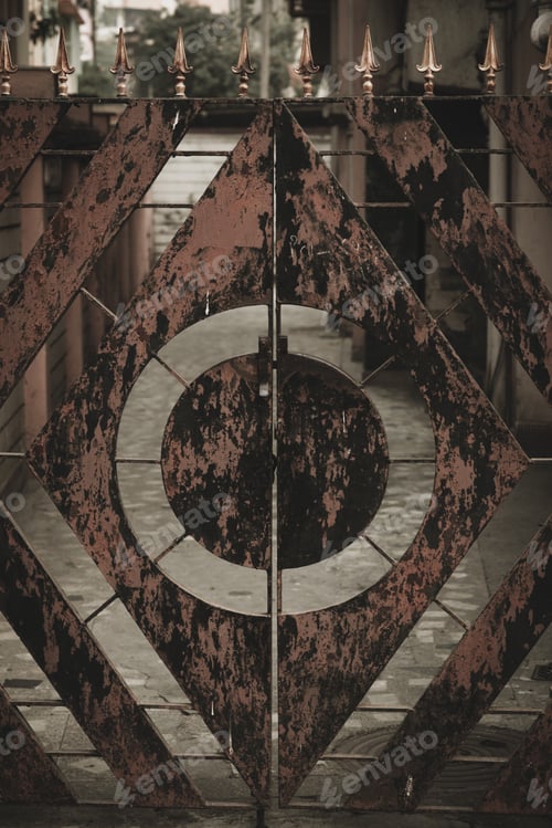 Preview: A Vertical Shot Of A Rusty Metal Fence With Circular And Diamond Shape Cutouts Inside A Building