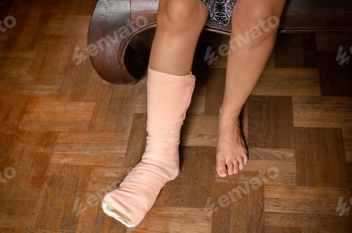 Preview: Injury Women Foot With Splint On The Leg Sitting On Couch At Home.
