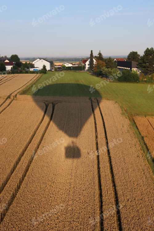 Preview: A Vertical Shot Of The Shadow Of A Big Hot-Air Balloon Over A Field Of Hay And Grass