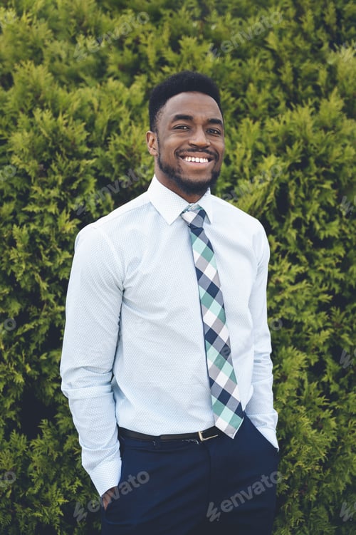 Preview: A Vertical Shot Of A Handsome African-American Male Posing On A Green Thuja Background