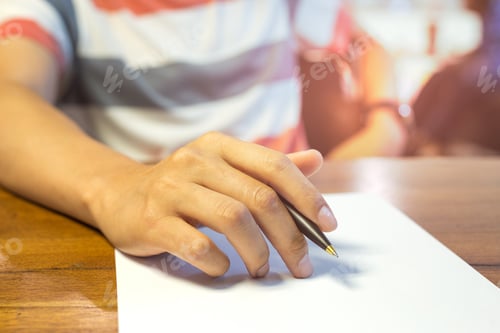 Preview: Male Hand Holding Pen Over Paperwork On Wooden Table