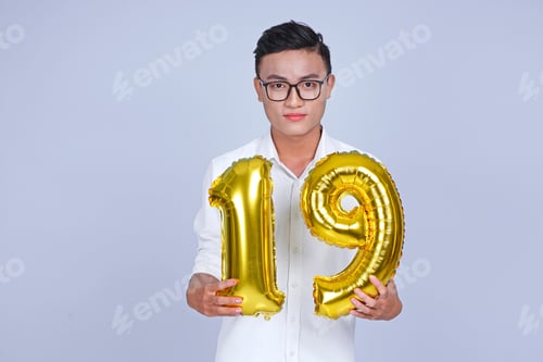 Preview: Asian Young Handsome Attractive Male Student Holding Metallic Foil Balloon With Number