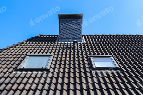 Preview: A Closeup Shot Of A Roof In Velux Style With Black Tiles On A Blue Sky Background