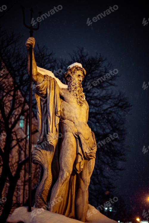 Preview: A Vertical Shot Of A Half-Naked Male Sculpture With A Long Beard Holding A Wand During Nighttime