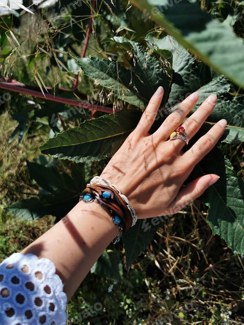 Preview: A Closeup Shot Of A Hand With Green Leaves In The Background