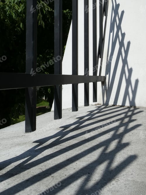 Preview: A Vertical Shot Of An Iron Fence And Shadows On The White Wall