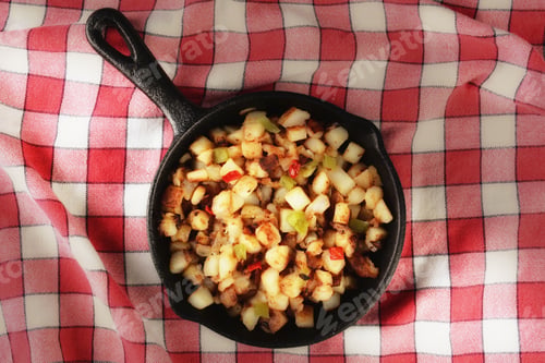Preview: High Angle Shot Of A Cast Iron Skillet With Country Style Hash Brown Potatoes On A Red Checked