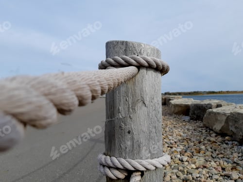 Preview: Closeup Of A Wooden Post With Heavy Rope To Act As A Waterside Roadway Guard Rail