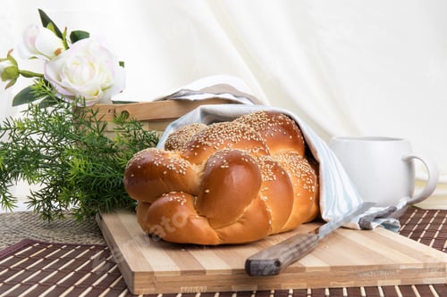 Preview: A Braided Loaf Of Sesame Challah Bread On A Wooden Cutting Board Covered In Cloth