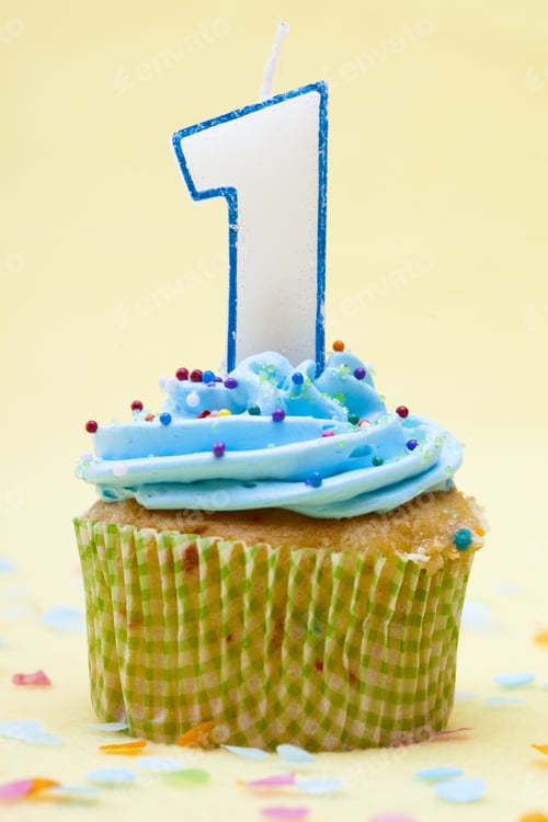 Preview: Close-Up Shot Of A Cupcake With Number 1 Birthday Candle Over Yellow Background.