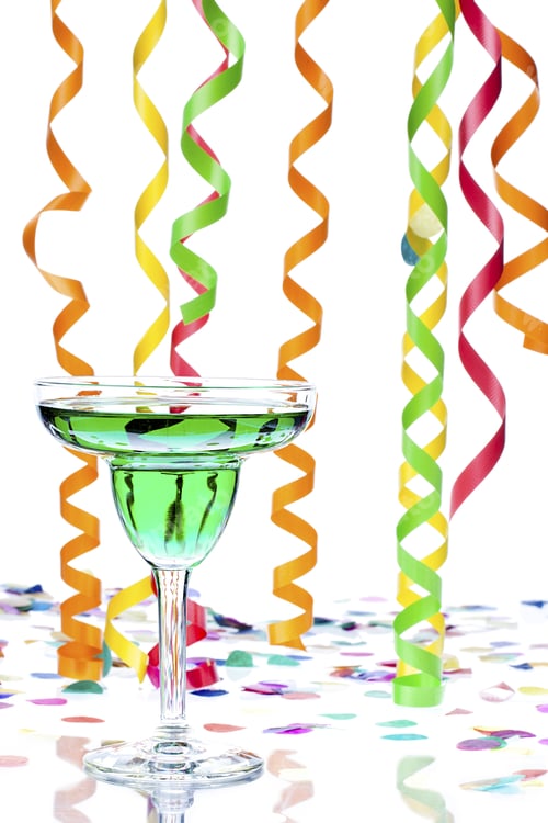 Preview: Close-Up Shot Of A Green Alcoholic Drink In Martini Glass With Colorful Streamers And Confetti In