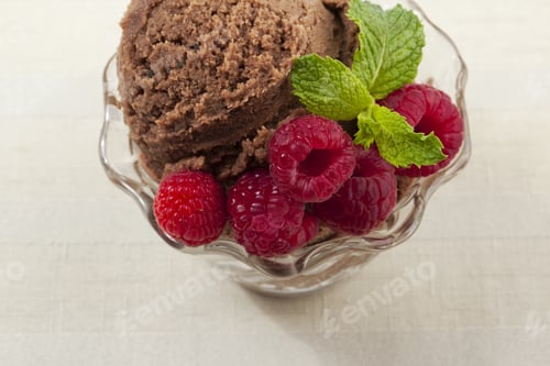 Preview: Close-Up Image Of Red Raspberries On The Side Of Creamy Chocolate Ice Cream