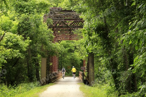 Preview: Male Bicyclist Riding Under An Old Railroad Bridge; Midwest; Horizontal