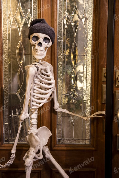 Preview: Halloween Skeleton Greeting At The Door Wearing A Knitted Hat