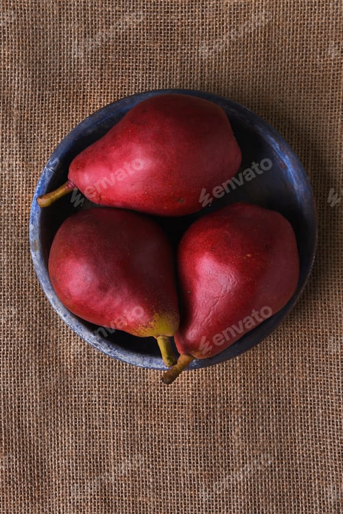 Preview: Blue Plate With Three Red Pears On A Burlap Surface. Vertical Format With Copy Space.