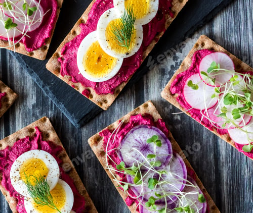 Preview: Top Down View Of Rye Wafer Crackers With Beet Hummus And A Variety Of Healthy Toppings And Garnish
