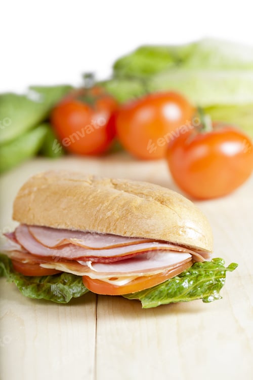 Preview: Vertical Image Of Ham Sandwich With Blurred Tomatoes And Vegetable On The Background