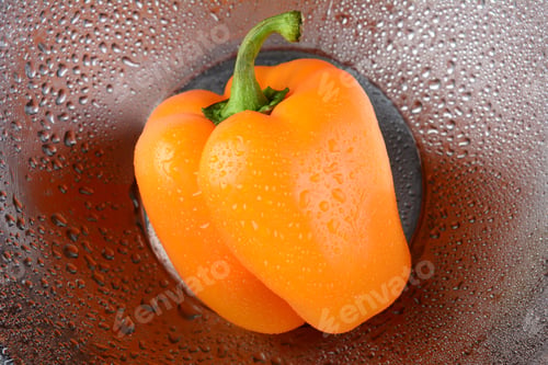 Preview: An Orange Bell Pepper In A Stainless Steel Bowl With Water Drops. Closeup With Shallow Depth Of