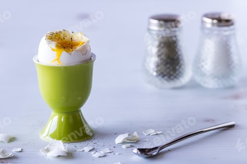 Preview: Close Up Of An Egg In An Egg Cup With Salt And Pepper Shakers In The Back Ground.